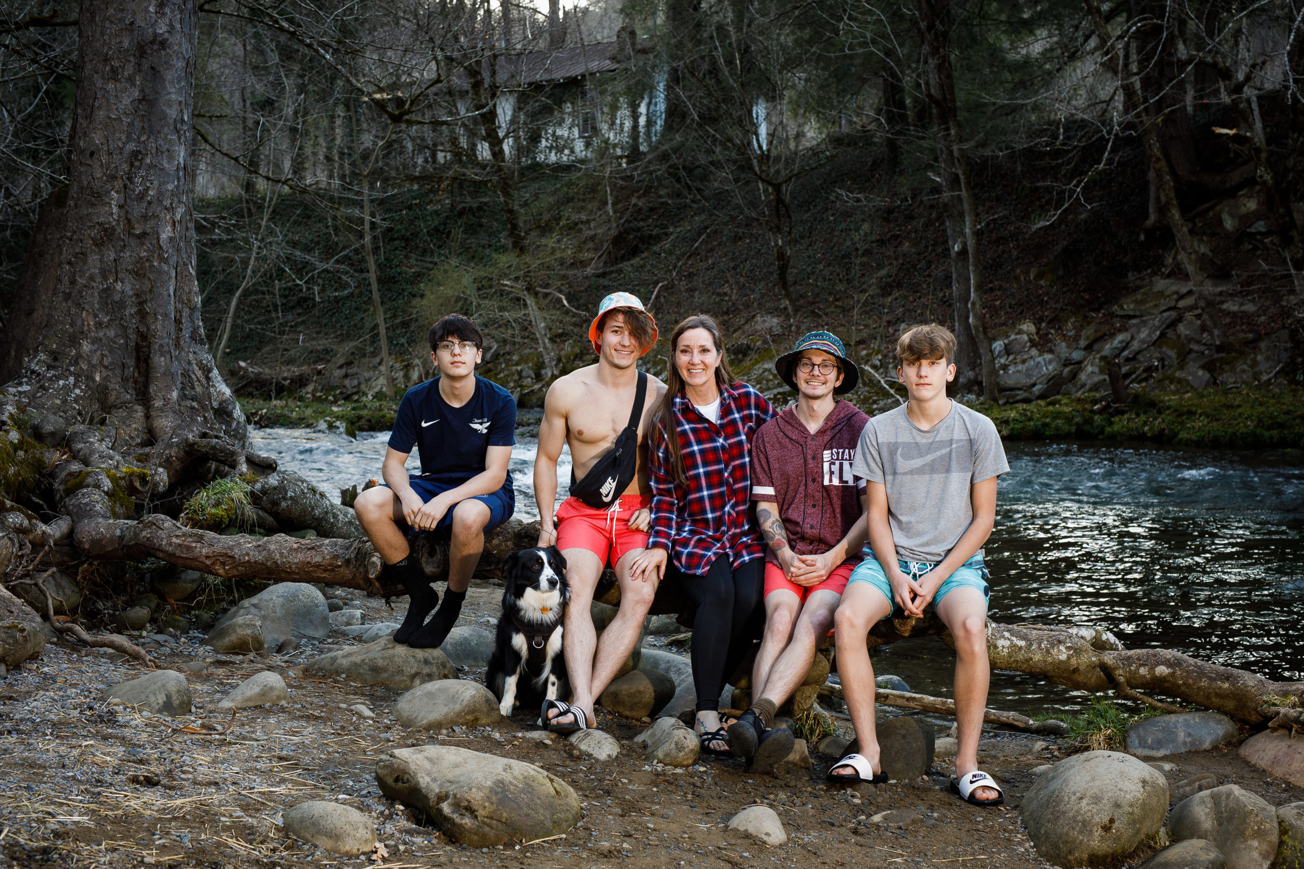 A mom with four boys and a dog sitting by a river